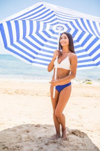 sun-protection-summer-body-care-concept-young-latin-woman-wearing-bikini-under-beach-umbrella-...jpg